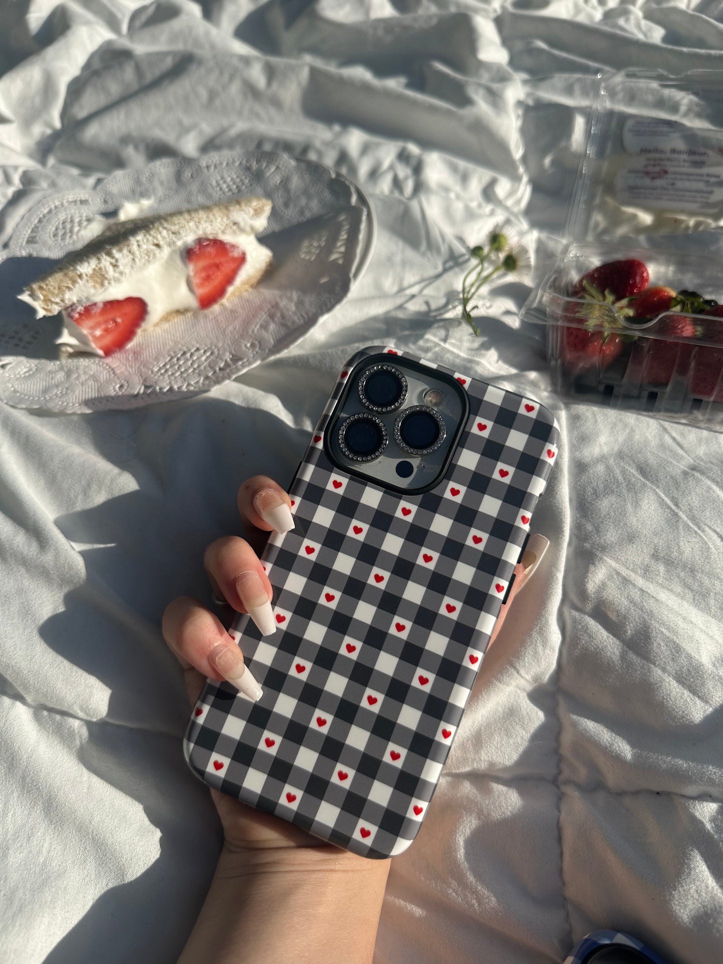 Magsafe Phone case black gingham checker plaid pattern with red hearts. Cute, simple protective cover for iPhone, Samsung, and Pixel. Prefect for spring and summer! modeled at picnic