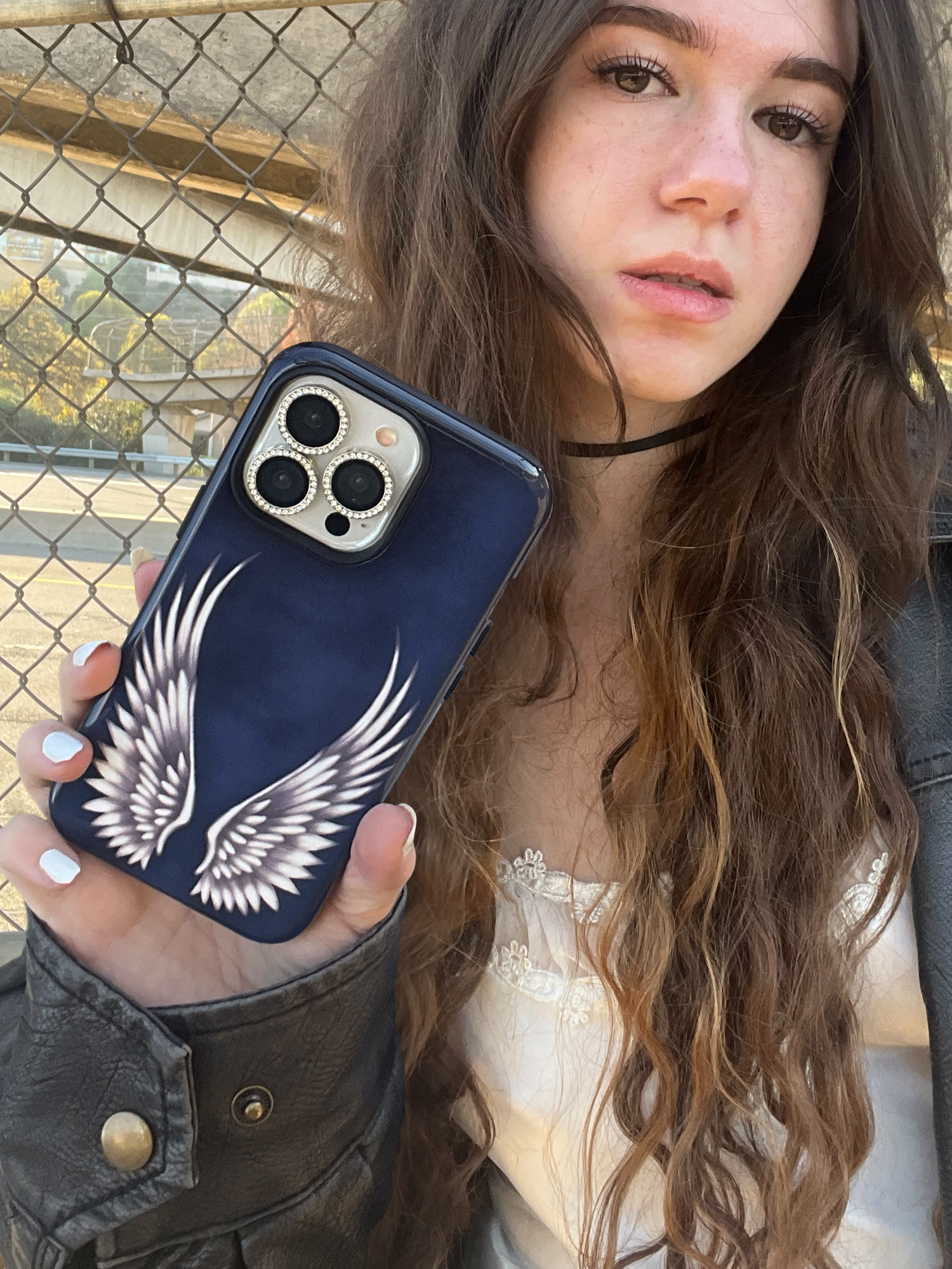 Navy blue phone case with white angel wings held front view with girl posing, protective, edgy, bold, aesthetic, grunge