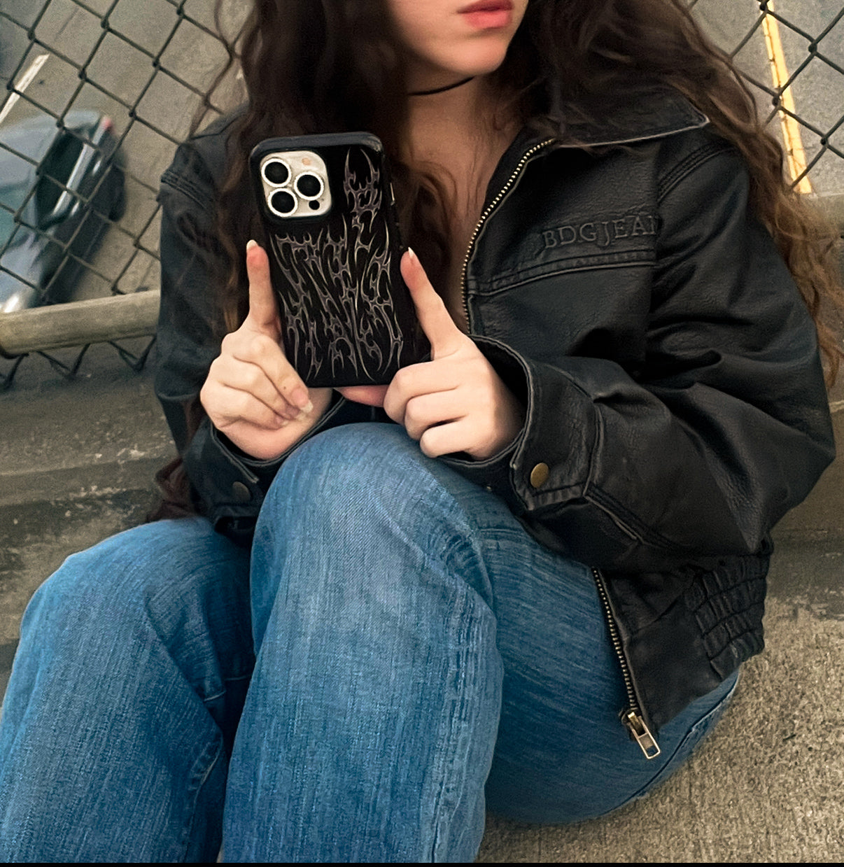 metal cyber cigilism black phone case with chrome silver daggers, protective and edgy held by model in leather jacket
