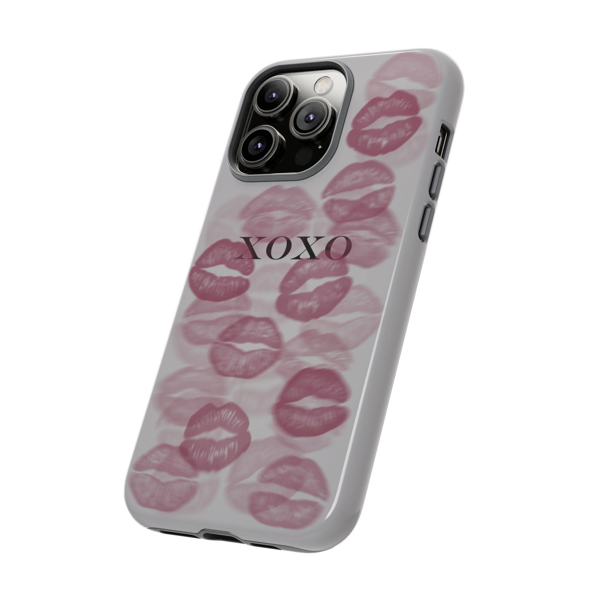 phone case with grey background, pink lipstick kiss marks dotted all around and black XOXO text in the middle, angled diagonal view