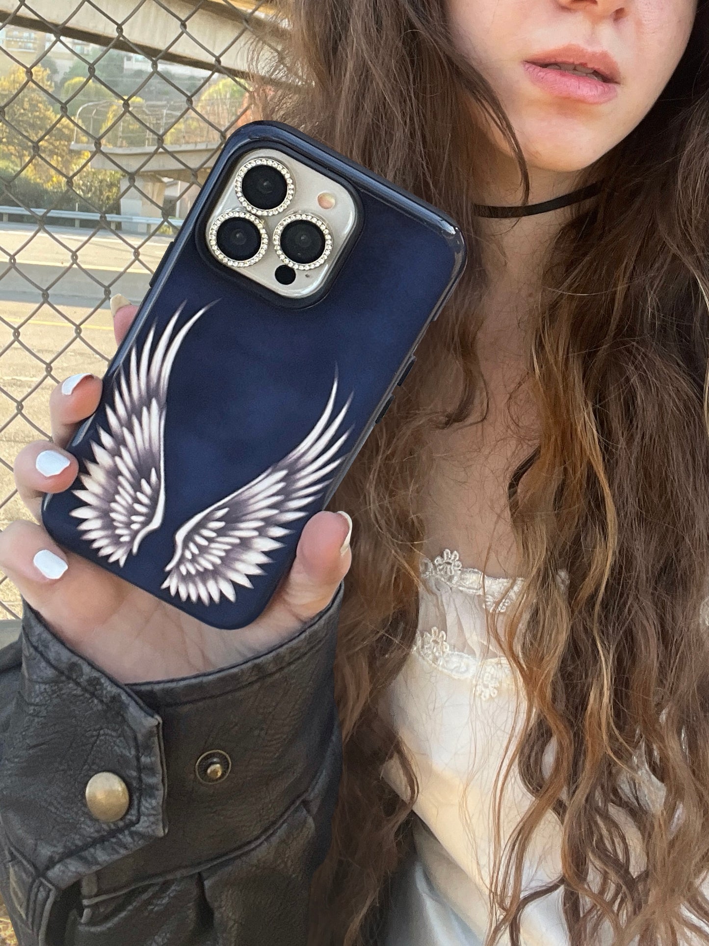 Phone case with white angel wings on blue background. cute, edgy, cool protective design. Fits iPhone, Samsung & Pixel. Perfect for boho chic outfit, modeled by girl